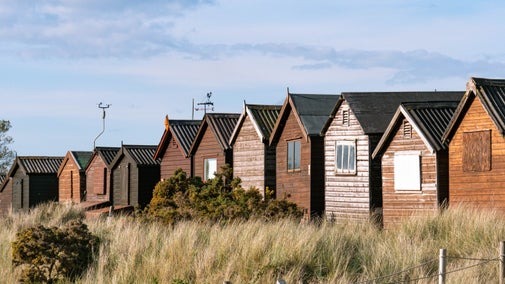 A row of beach huts with the evening sky behind them in spring at Studland Bay, Dorset